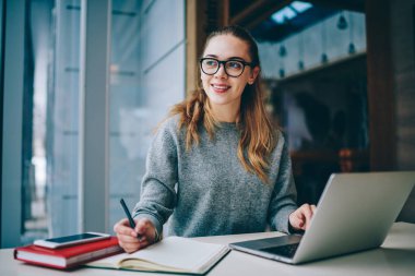 Modern netbook üzerinde arama bilgi kapalı kız öğrencinin harcama zaman üniversite kütüphanesi, mutlu kadın dizüstü bilgisayar kullanan öğrenme dil için bu geliştirici rahat olumlu giyinmiş