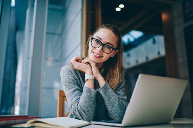 Teknoloji ve iletişim, modern netbook ile yer yüzünde gülümsemeyle kameraya bakarken coworking, vakit Eyewear mutlu müreffeh kadın serbest meslek portresi kavramı