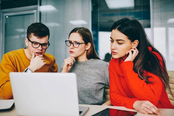 Dalgın yetenekli öğrencileri ile birlikte izlerken ciddi yüzler webinar Web sitesinde seminer için hazırlama alanı coworking içinde kablosuz internet bağlantısını kullanarak modern dizüstü bilgisayar eğitim