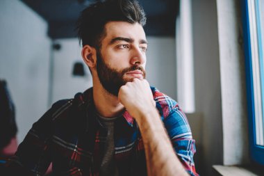 Dalgın hipster adam giymek rahat giyim düşünceli uzak kapalı otururken bakarak, rüya beyaz adam öğrenci yarın sınav ve bekleyen arkadaş üniversite kampüsü hakkında düşünme sakallı