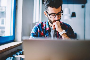 Düşünceli erkek metin yazarı alan, konsantre adam için kablosuz bağlıyken netbook kullanarak yeni Web sayfası oluşturma hakkında düşünme coworking, modern dizüstü bilgisayar ile vakit gözlük