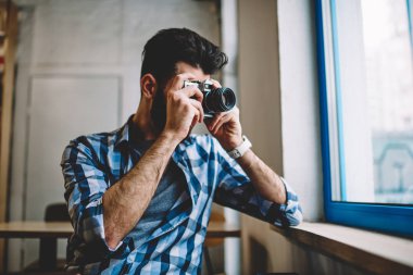 Yetenekli yaratıcı beyaz hipster adam genç profesyonel erkek fotoğraf görüntü retro eski moda teknolojisi ile kapalı alarak kafeterya penceresini vintage fotoğraf makinesi kullanarak resim yapma