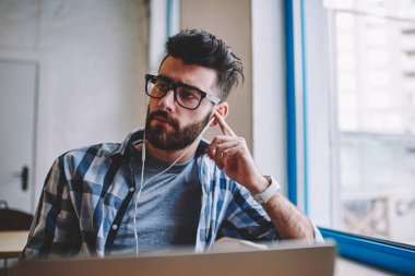 Düşünceli hipster adam bir kenara süre dinleme ilginç radyo sinyalleriyle iletilen kitap elektronik kulaklık üzerinden tatilinde e öğrenme laptop, dalgın Genç beyaz adam alan coworking adlı müzik keyfi arıyor