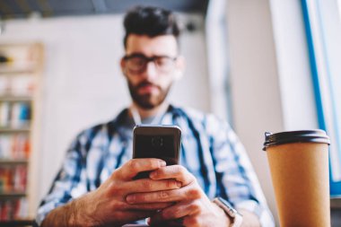 Cep telefonu ve paket servisi olan restoran kahve, sosyal ağlar, uzay coworking 4 g bağlantı ile modern smartphone kullanarak metin mesajı yazmaya genç hipster adam erkek ellerinde seçici odak