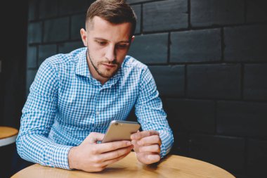 4 g internet bağlantısı kullanarak modern smartphone aygıt üzerindeki mali haber okuma dalgın genç adam. Hippi erkek blogger sohbet ve kafe iç oturan telefonu dosya indirme