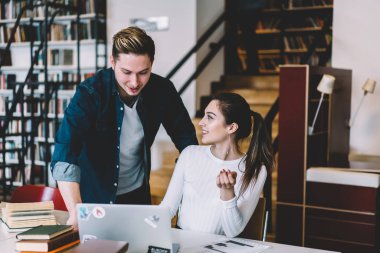 Dizüstü bilgisayar, netbook öğrenme sırasında app yükleme yetenekli meslektaşı ile danışmanlık olumlu hippi kız kullanan ödev işbirliği sırasında konuşurken gülümseyen kadın ve erkek öğrenciler