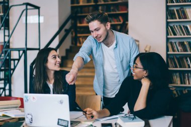 Proje alanı, öğrencilerin ders araştırma için netbook kullanarak üzerinde işbirliği olumlu çok ırklı mürettebat coworking yılında meslektaşları ile tartışırken dizüstü bilgisayarda işaret mutlu hipster adam 