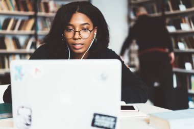 Genç Afro-Amerikan kadın freelancer Eyewear dizüstü bilgisayarda çalışarak vizyon koruma için konsantre koyu tenli öğrenci izlerken öğretici online campu online ders öğrenme