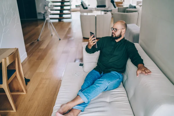 Ernster Bärtiger Junger Mann Mit Brille Sitzt Auf Dem Sofa — Stockfoto