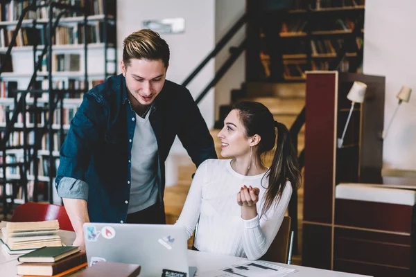 Dizüstü bilgisayar, netbook öğrenme sırasında app yükleme yetenekli meslektaşı ile danışmanlık olumlu hippi kız kullanan ödev işbirliği sırasında konuşurken gülümseyen kadın ve erkek öğrenciler