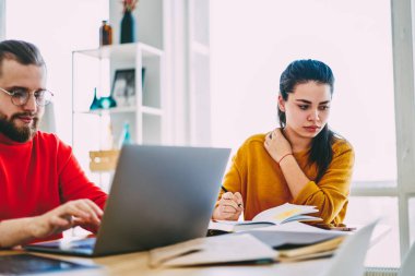 Dizüstü bilgisayar, girintili coworking işbirliği ortak proje üzerinde hipster ortakları kullanarak meslektaşım yanında oturan ev ödevi dalgın kız öğrenci düşünceli uzağa bakarak konsantre