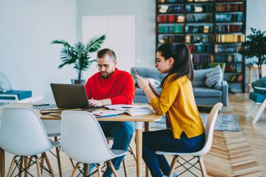 Genç kadın, erkek arkadaşı ise ağ sohbet için Smartphone kullanarak dizüstü bilgisayar, hipster kadın ve erkek hom Internet bağlantısı kullanarak üzerinden uzaktan serbest iş konsantre