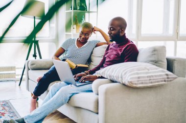 Pozitif koyu tenli evlilik ev iç, Afrikalı-Amerikalı kadın kocası dizüstü bilgisayar bloglama wifi bağlantısı üzerinden sosyal ağlar üzerinde yazarak kitabı okuma ücretsiz zaman harcama