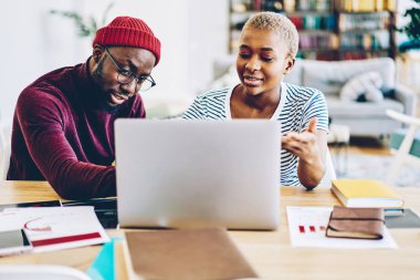 Evinizde öğeleri tartışırken dizüstü bilgisayar üzerinden web mağazasında alışveriş yapma genç Afro-Amerikan çift erkek ve dişi hipsters online fotoğraf ile ilgilenen birbirinizle konuşmak iç, koyu derili