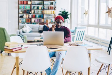 Web sitesinde, yetenekli Afro-Amerikan freelancer rezervasyon teyit ederken cep telefonu üzerinde konuşurken ciddi koyu tenli hipster adam telefon görüşmesi ve browsin online iş üzerinde konsantre