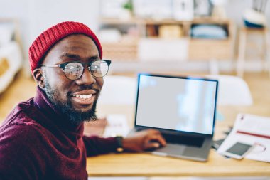 Koyu tenli hipster adam Eyewear sahte ekranı, yetenekli başarılı Afro-Amerikan serbest portresi ile laptop yanında oturan kamera seyir vizyon koruma için tarih seçici odak