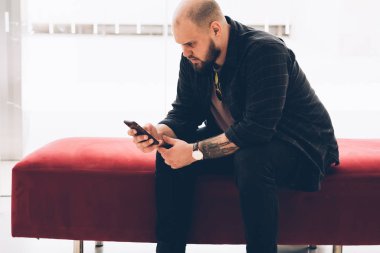 E-posta kontrol ve akıllı telefon elinde tutan bildirim okuma rahat kıyafet giymiş adam dalgın Genç sakallı. Erkek blogger App 4 g telefon üzerinde yükleme konsantre Internet