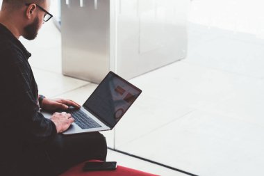 Genç adam Freelancer kırpılmış görünümü modern dizüstü tutarak ve 4 g Kablosuz Internet bağlantısı'nı kullanarak yüklemek için app güncelleme rahat kıyafet giymiş. Kopyalama alanı alanı reklam için