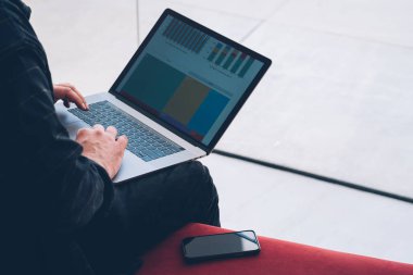 Modern dizüstü bilgisayar klavye üzerinde metin yazarak ve uzaktan kablosuz internet kullanarak mali grafikler oluşturmaya çalışan adamın elleri görünümünü kırpılmış. Diyagram üzerinde görüntü ile modern netbook