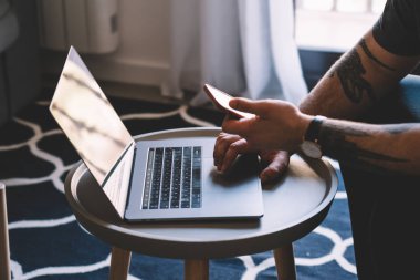 Web sitesinde modern dizüstü bilgisayar ve netbook üzerinde USB'yi bluetooth connection.man'ın ellerini kullanarak smartphone üzerinde paylaşım ortam dosyaları hakkında bilgi ararken hipster adam görünümünü kırpılmış