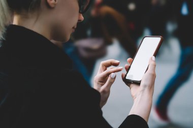 Modern smartphone elinde tutan ve gadget boş ekranda metin mesajı yazmaya genç kadın arkadan görünüm kırpılmış. Kadın blogger içerik için nazlı yer alan telefon aygıtındaki App yükleme