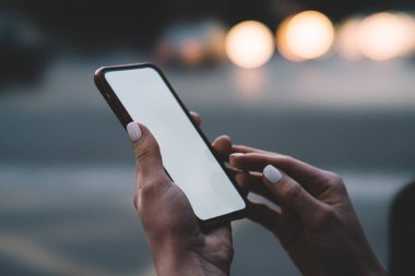 Kadının elleri boş ekran alanı ile modern smartphone aygıt Internet içeriği veya Web sitesi için bokeh arka planda tutan görünümünü kırpılmış. Sahte alanı ile dijital cep telefonu