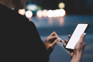 Kadının elleri boş ekran alanı ile smartphone aygıt Web siteniz için holding ve 4 g kullanarak uygulama yükleme kırpılmış yan görünüm Internet üzerinde bokeh arka plan ile gece ışık