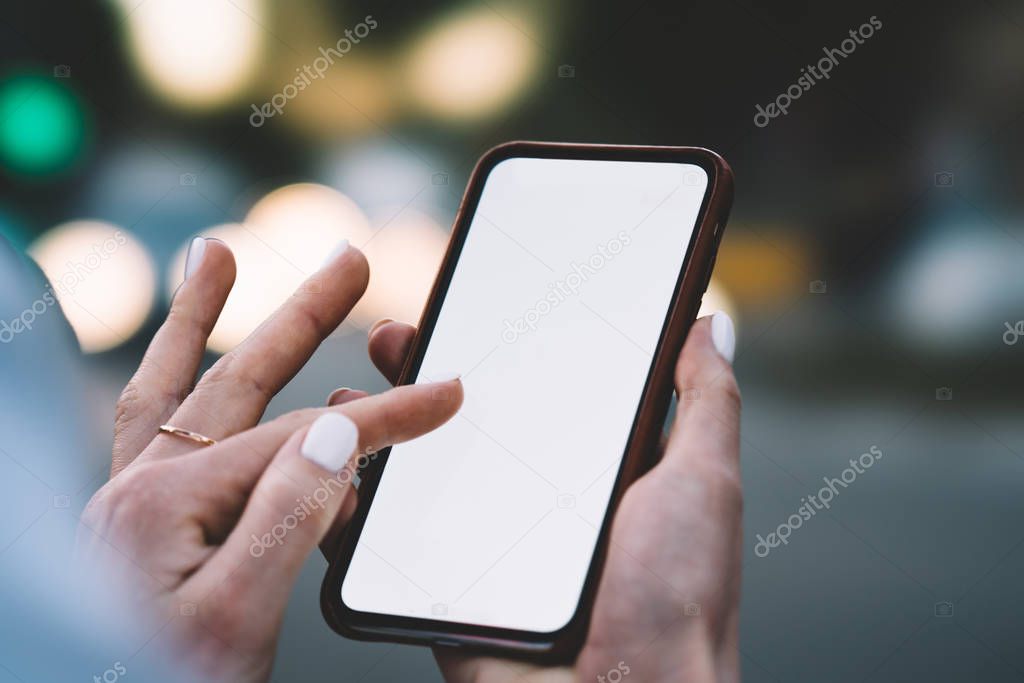 Cropped view of female fingers touching on blank screen of modern smartphone and making payment online on website using 4G internet connection.Woman's hands holding mobile phone with copy space area