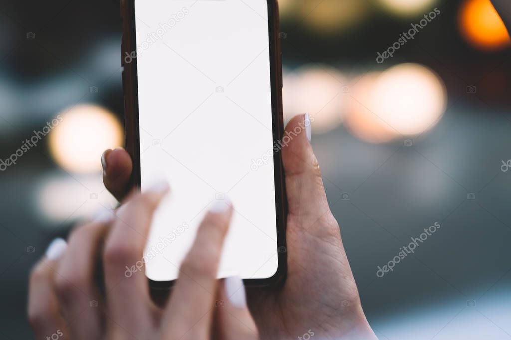 Cropped view of modern smartphone with female finger typing sms message on blank display of digital device.Woman's hands holding mobile phone with copy space area for your internet content