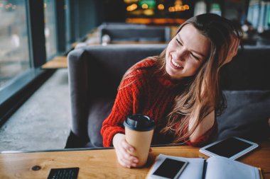 Mutlu başarılı kız öğrencinin öğrenme ve eğitim, üniversite kampüsü masada oturan kafein içecek ile paket servisi olan restoran Kupası tutan pozitif kadın tatilinde kahve dükkanında latte zevk