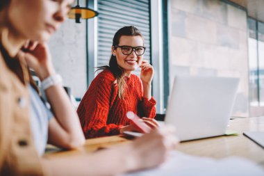 Gülümseyen kadın serbest meslek sağlamak gözleri koruma kameraya coworking uzayda genç neşeli hippi kız arkadaş kapalı oturan Dizüstü aygıtı ile seyir için gözlük portresi