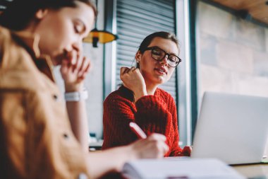 Genç meslektaşım ve dizüstü bilgisayar aygıt Kampüsü ile vakit zeki beyaz kadın kapalı, masada oturan onun kız arkadaşı oluşturma planı arıyorum gözlük hippi kız ilgi