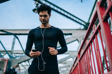 Cep telefonu 4 g bağlantı sırasında egzersiz açık havada, aktif erkek koşucu telefon yayınlamaya başlamak önce çalma listesi şarkıları motivasyon kontrol kullanarak mesaj okuma eşofman ciddi adam