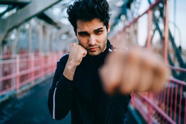 Championat için hazırlamak için yarım uzunluk portre konsantre adam boksör gücü yapıyor yumruklar ve kardiyo eğitim açık havada sırasında kameraya baktığımızda, Erkek bulanık cephe süsleme yumruk sıkılı