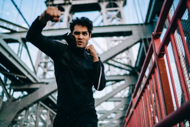 Eşofman pratik ve iş güç yumruk şehir Köprüsü'nde, ciddi adam konsantre sporcu eğitim ve egzersiz süreç, sağlıklı yaşam biçimi ve hedef için motivasyon kavramı üzerinde boks