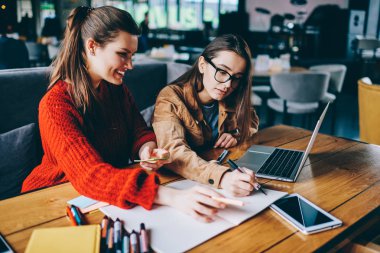 Pozitif kadın grafik tasarımcıları birlikte teknoloji ve bilgi kavramı defter, yenilikçi kızlar zaman zevk ve birlikte, öğrenme gülümseyen kullanarak çizimler çizim kafeteryada çalışan