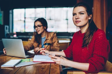 Düşünme ve uzak el kadın genç öğrenme Kampüsü için dizüstü bilgisayar kullanan yakındaki eğitimi için ders kitabı ile oturan smartphone aygıt ile seyir çekici düşünceli hippi kız