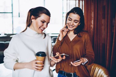 Neşeli kadın blogcular akıllı telefonlar, zaman takipçileri üzerinden cep telefonları kahve dükkanında dinlenme ile birlikte sohbet tadını kadın gülümseyerek olumlu bluetooth bağlantısı ile bilgi paylaşımı