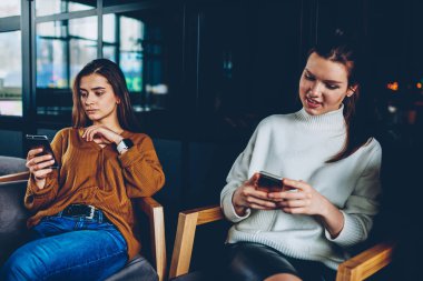 Konsantre kadın genç gülümseyen süre 4 g bağlantısıyla cep telefonu kullanarak hareket için uygulama ile ödeme yapma yakın oturan ve takipçileri cep telefonu ile mesajlaşma kadın arkadaş