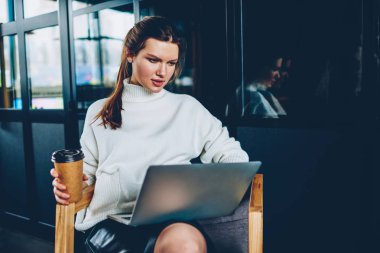 Ciddi kadın yazılım geliştirici çalışma için paket servisi olan restoran kahve tutarak ve bilgisayar servis öğrenme önemli webinar izlerken kafkas kadın Dizüstü aygıtı kullanarak program kodunu yazarak Web sayfası oluşturma