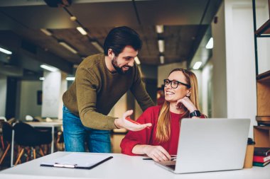 Genç erkek arkadaşı tarafından iki gülümseyen hipsters blogcular birlikte kapalı yaratma komik video vlog hatırlıyorum ayakta ile dizüstü bilgisayarda çalışırken break zevk gözlük çalışan çalışmalarında