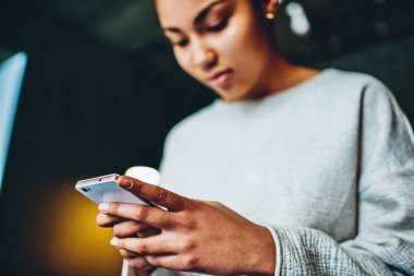 Sohbet, sohbet ve mesajları online gönderme için sosyal ağları sohbet Genç koyu tenli kadının elinde telefon seçici odak için smartphone tutan dalgın Afro-Amerikan Kız