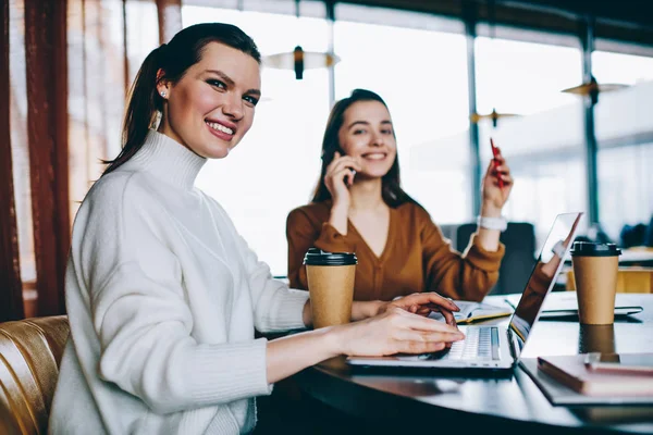 微笑千年女性文案的肖像坐在桌面上的笔记本电脑设备使用自助餐厅 Wifi 两位女博主花时间一起在咖啡店浏览互联网上的上网本 — 图库照片