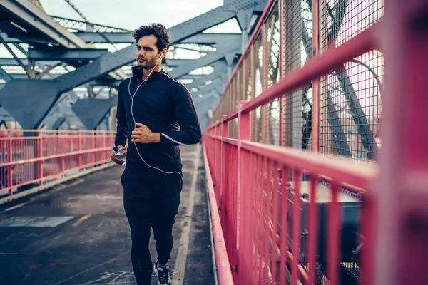 运动的人与肌肉的身体运行横跨城市桥梁与瓶子在手 年轻的慢跑运动员在户外享受有氧运动和锻炼 欧洲选手努力实现目标 — 图库照片