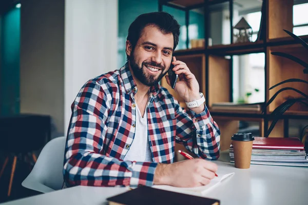 Poz ve telefonla, konuşma yaparken kameraya bakarak mutlu yakışıklı hipster adam portresi smartphone için çağrı kapalı kahve molası sırasında kullanımı ve öğrenimi olumlu erkek öğrenci