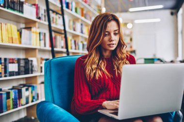 Üniversitesi Kütüphanesi'nde oturan ve dizüstü aygıtta genç hippi kız yetiştirdim bilgileri modern Netbook için wifi bağlı arama öğrenme e için vakit sevimli kız öğrenci