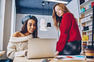 Çok kültürlü kız öğrencilerin online kurslar Dizüstü aygıtı ve wifi bağlantısı kapalı, trendy hipster kızlar tarassut video yolu ile medya app netbook üzerinde sosyal ağlar kullanarak e öğrenme için arama