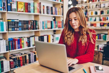 Sevimli kız öğrencinin Üniversite Kütüphanesi, hippi kız iş vacancy yolu ile app netbook üzerinde soran e-posta yazarak Internet Information dizüstü cihazdan kullanarak başlangıç proje için araştırma yapma