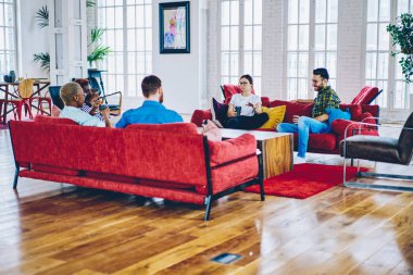 Genç takım yaratıcı erkek ve kadın meslektaşları, modern iç kırmızı kanepe üzerinde oturan fikirler tartışırken zevk teen çok ırklı hipsters birbirinizle konuşmak boş zaman harcama ve fu var