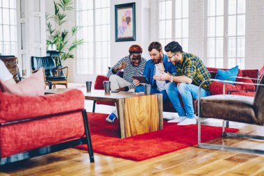 Neşeli erkek hipsters izlerken maç online dijital tablet ücretsiz birlikte modern tasarlanmış çatı iç, çok ırklı vakit kontrol sonuçlarını çocuklar touchpa üzerinde bilgisayar oyununda seviye geçmek